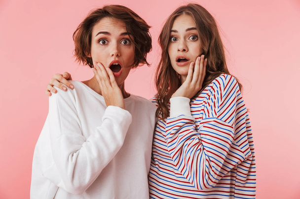 Image of shocked excited women friends isolated over pink wall background posing. - Foto, Imagen