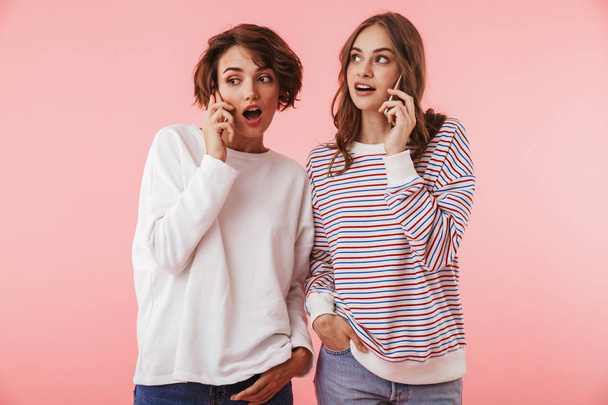 Image of happy women friends isolated over pink wall background talking by mobile phones. - Valokuva, kuva