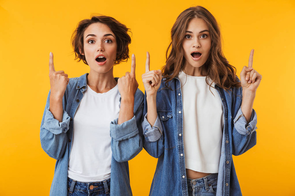 Image of amazing smiling emotional young women friends posing isolated over yellow background pointing. - Фото, зображення