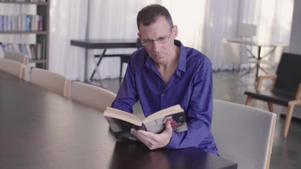 Empresário lendo um livro em uma biblioteca tiro aberto câmera lenta
 - Filmagem, Vídeo