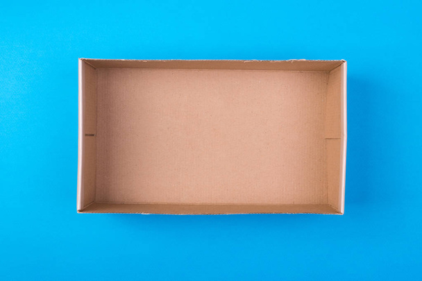 empty cardboard paper box on blue background. delivery concept, top view. - Photo, Image