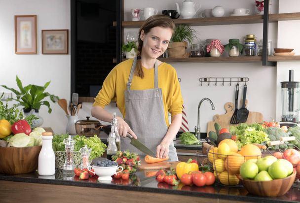 Здорова молода жінка на кухні готує фрукти та овочі для здорового харчування та салату
 - Фото, зображення