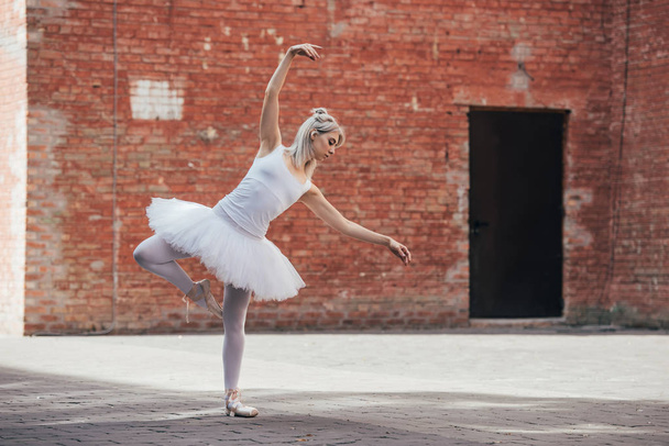full length view of elegant young ballerina dancing on city street  - Фото, зображення