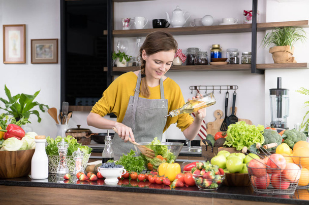 Mujer joven y saludable en una cocina preparando frutas y verduras para una comida saludable y ensalada
 - Foto, imagen