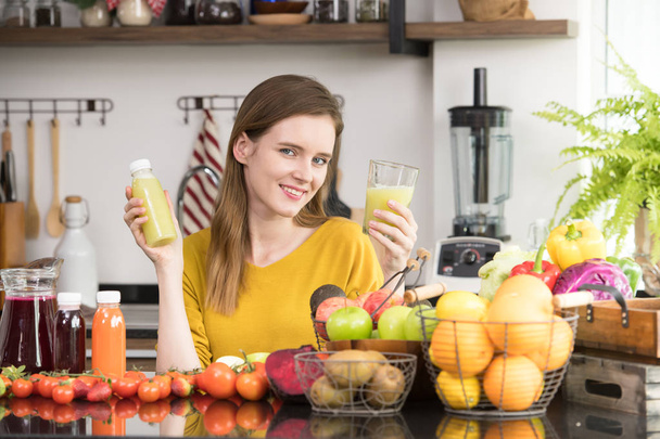 Здоровая молодая женщина на кухне с фруктами и овощами и соком
 - Фото, изображение