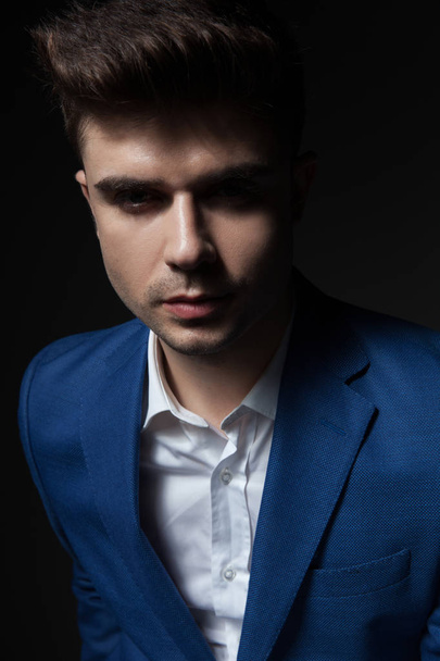 portrait of young and handsome man wearing a blue suit while standing on black background - Photo, Image