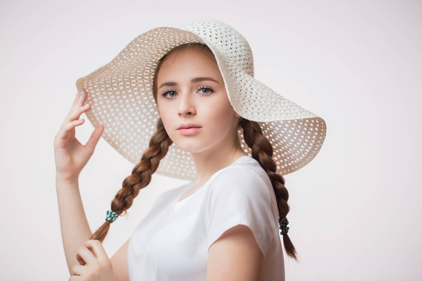 Portrait of beautiful young woman in summer light hat and t-shirt on white background. Charming student girl looking at the camera. Human emotions, facial expression concept - Foto, Imagem
