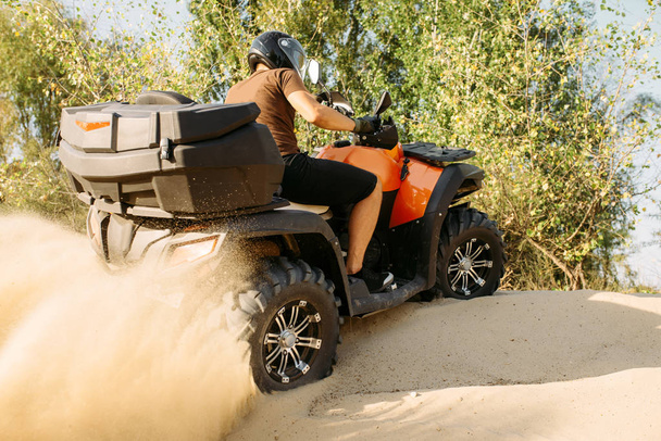 Atv は、アクション、背景、極端なスポーツに砂の採石場で乗馬します。砂場でクワッド バイクのヘルメットで男性ドライバー - 写真・画像
