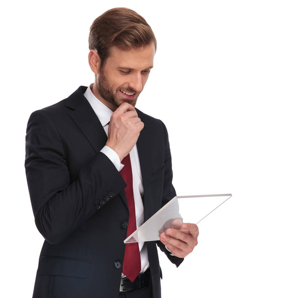 portrait of pensive businessman reading from transparent gadget while standing on white background - Photo, image