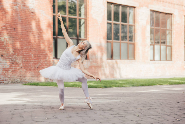 attractive young ballerina in pointe shoes dancing on urban street    - Fotoğraf, Görsel