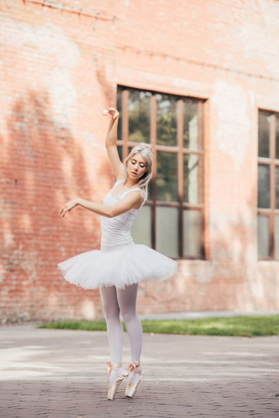 beautiful young ballerina in pointe shoes dancing on urban street   - 写真・画像