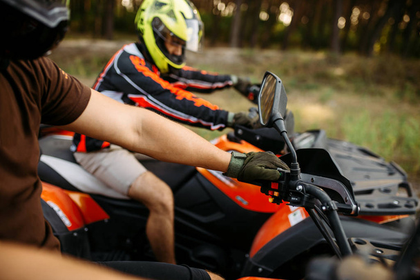 旅行、サイドビュー、背景に夏の森の前にヘルメットの 2 つのバギーのライダー。男性 quadbike ドライバー、atv の乗馬、アクティブな旅行 - 写真・画像