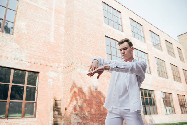 handsome young male dancer in white clothes dancing on street   - Fotografie, Obrázek