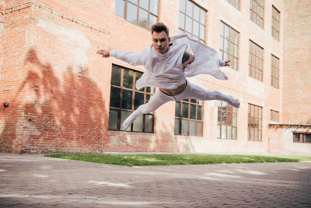 low angle view of young ballet dancer in jump on city street   - Fotografie, Obrázek