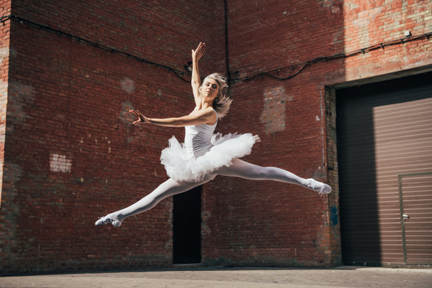 beautiful young ballerina jumping and dancing on urban street  - Photo, Image