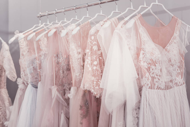 Beautiful wedding dresses hanging on hangers in the shop - 写真・画像