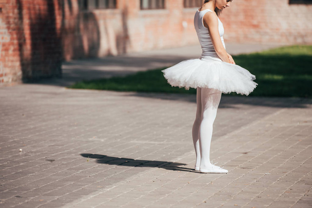 oříznuté záběr baletka v bílých tutu sukně stojící na ulici - Fotografie, Obrázek