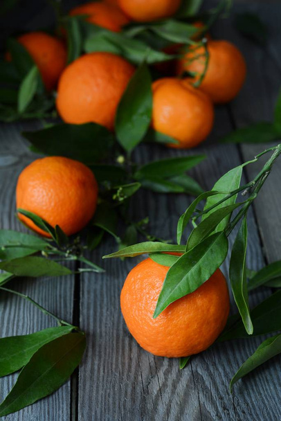 Tangerines (oranges, mandarins, clementines, citrus fruits) with leaves in basket on Gray background. Mandarin oranges with leaves in white basket on rustic wood background. Citrus - 写真・画像