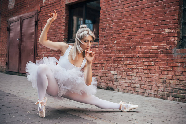 beautiful young ballerina looking at camera while dancing on street  - Valokuva, kuva