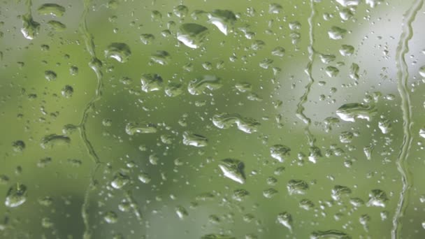 Nahaufnahme von Wassertropfen auf Fensterglas mit unscharfem natürlichen Hintergrund - Filmmaterial, Video