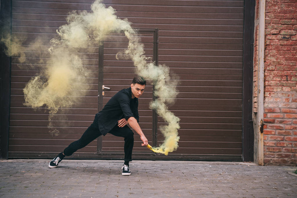 Nuori mies tanssii keltaisessa savussa kaupungin kadulla
 - Valokuva, kuva