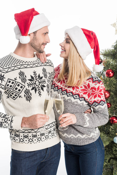 young couple in love clinking glasses of champagne near christmas tree isolated on white - Foto, Bild