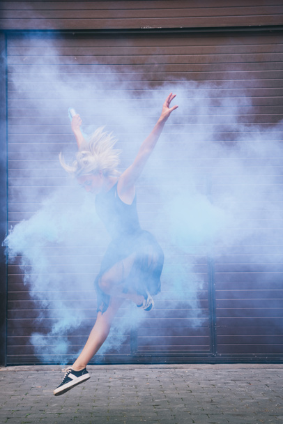 young contemporary dancer dancing in blue smoke on street  - Фото, изображение