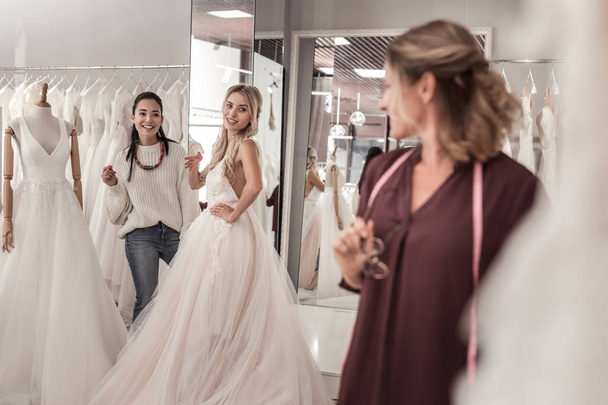 Joyful young women looking at the wedding dress designer - Foto, imagen