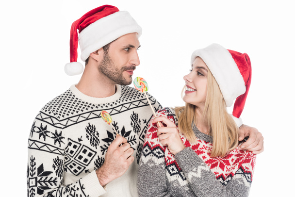 portrait of caucasian couple in santa claus hats with lollipops isolated on white - Fotografie, Obrázek