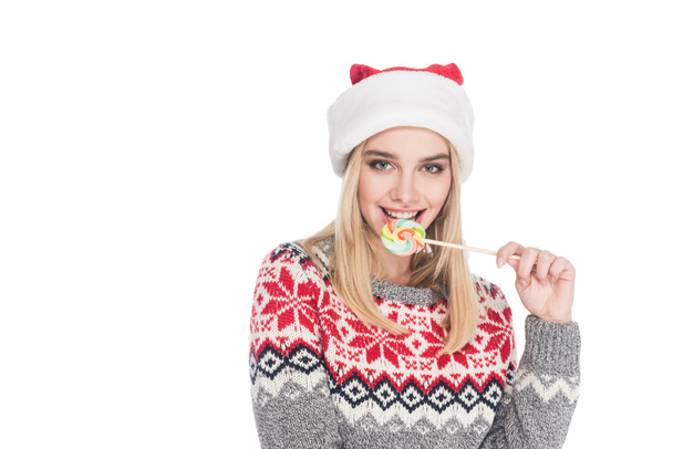 portrait of woman in sweater and santa claus hat with lollipop isolated on white - Фото, изображение
