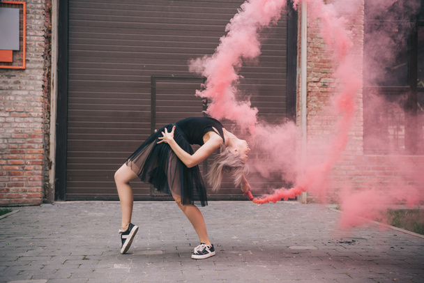 menina flexível dançando em fumaça rosa na rua urbana
   - Foto, Imagem