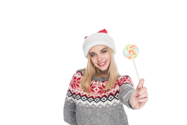 portrait of young woman in sweater and santa claus hat with lollipop isolated on white - 写真・画像