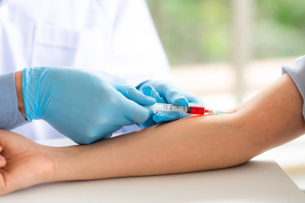 Close up shot of doctor using syringe takes blood from patient arm vein for medical test - Fotó, kép