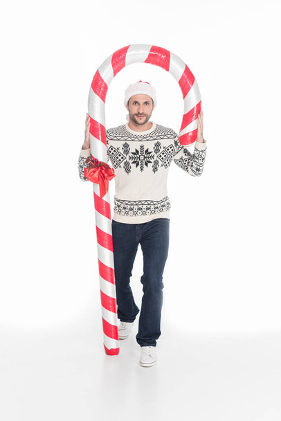 young man in sweater and santa claus hat with toy candy isolated on white - Foto, Bild
