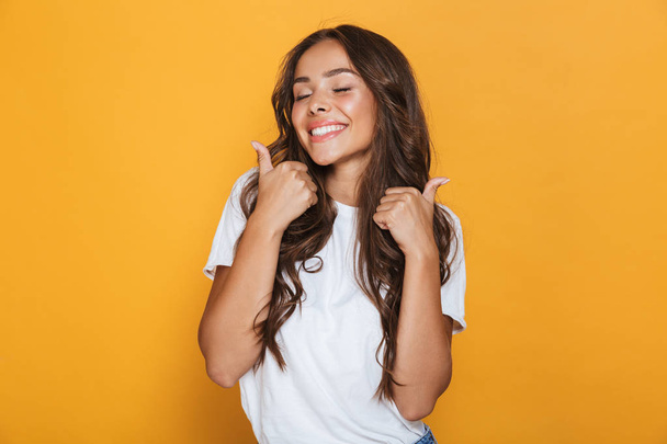 Image of happy young woman isolated over yellow background showing thumbs up gesture. - Foto, Bild