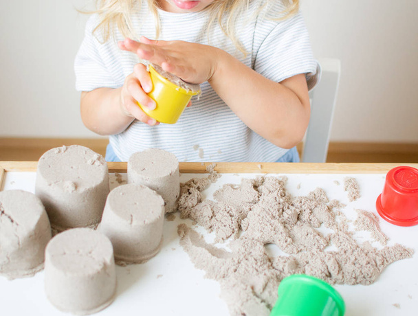 Pieni valkoihoinen tyttö leikkii kineettisen hiekan kanssa kotona Varhaiskasvatus Valmistautuminen koulun kehittämiseen Lasten peli
 - Valokuva, kuva