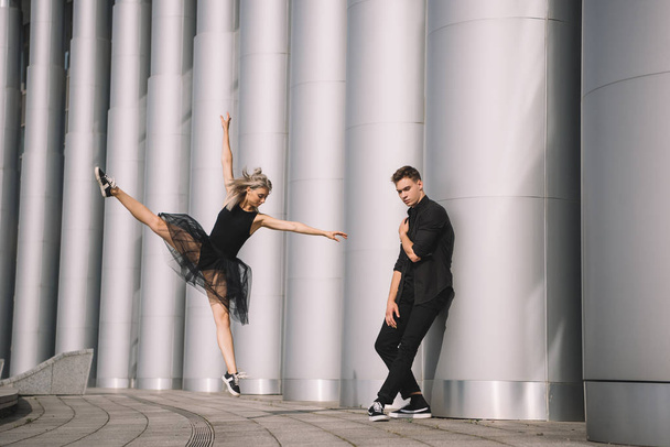 jong koppel van dansers in zwarte kleding dansen in de buurt van kolommen    - Foto, afbeelding