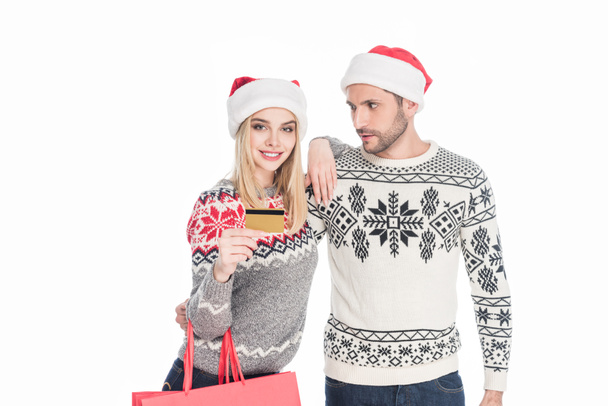 portrait of couple in santa claus hats with shopping bags and credit card isolated on white - Φωτογραφία, εικόνα