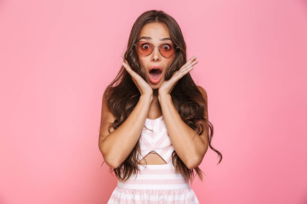 Photo of surprised woman 20s wearing sunglasses screaming at camera isolated over pink background - Foto, Imagem