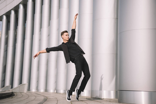 guapo joven bailarín moderno bailando cerca de columnas
 - Foto, Imagen