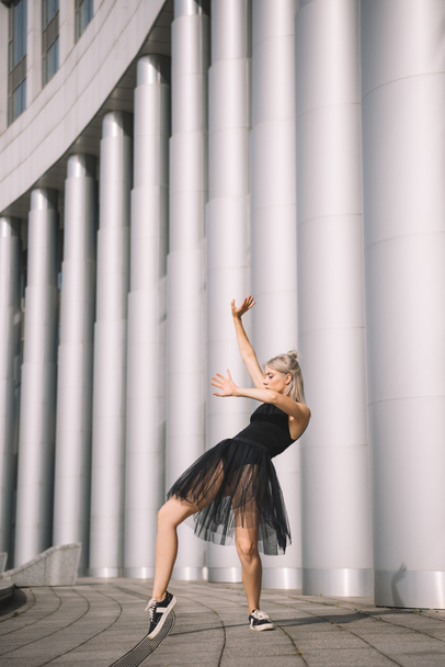 attractive girl in black skirt dancing near columns on street  - Foto, Imagem