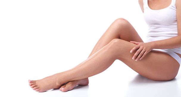 The legs of a young girl, part of the female body, tanned skin, body care, female legs isolated on white background, healthy and clean skin, health care, girl in underwear, french pedicure. - Photo, Image