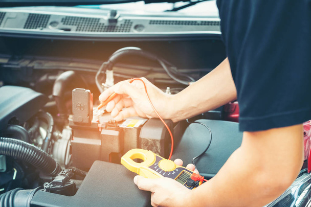 Close-up van gereedschap en mannen hand van mechanische auto reparatie tijdens onderzoeken oorzaak van het probleem (elektrische systeemcontrole) of werken aan auto benzine of dieselmotor bij garage - Foto, afbeelding