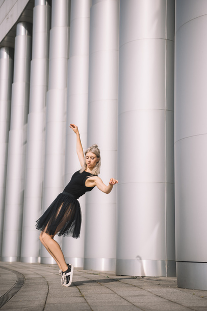 beautiful girl in black skirt dancing near columns  - Photo, image