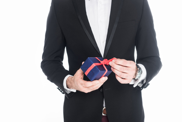 cropped shot of man in stylish suit holding wrapped present isolated on white - Fotó, kép