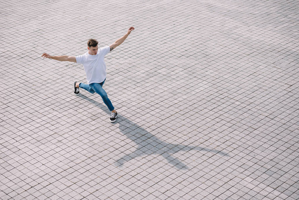 high angle view of handsome young man performing contemporary dance on street   - Photo, image