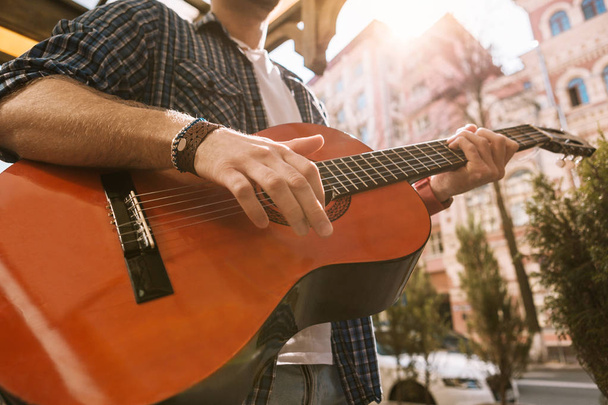 Male appealing guitarist playing music on street - 写真・画像
