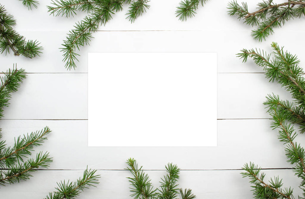 Creative Christmas layout. Fir twigs on white wood background whit copy space.Border arrangement. Flat lay top view.  - Foto, Imagen