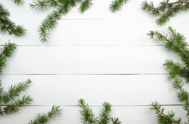 Creative Christmas layout. Fir twigs on white wood background whit copy space.Border arrangement. Flat lay top view.  - Photo, Image
