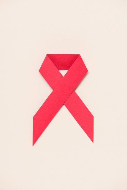 top view of HIV and AIDS awareness red ribbon on beige - Photo, image